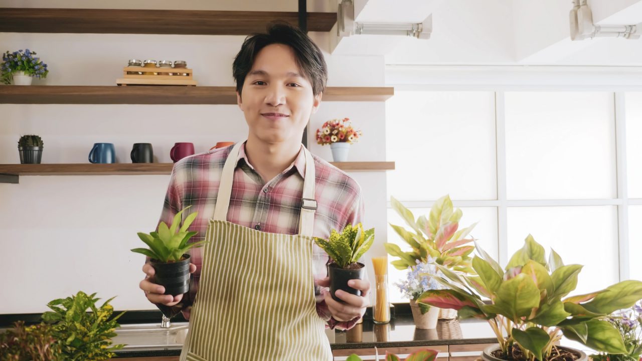 young gardener man holding flowerpot in the room e1650125663604